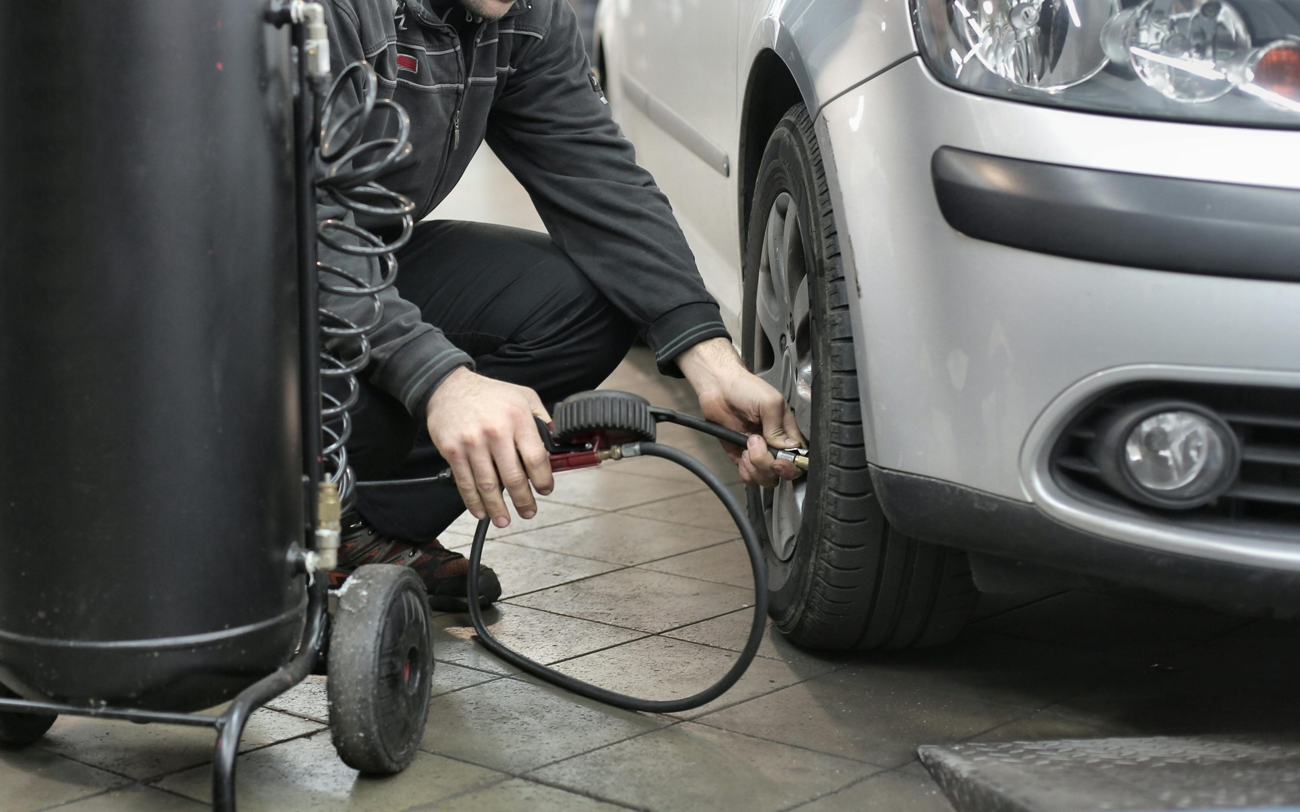 person filling a car tyre up with air as a pre MOT test check