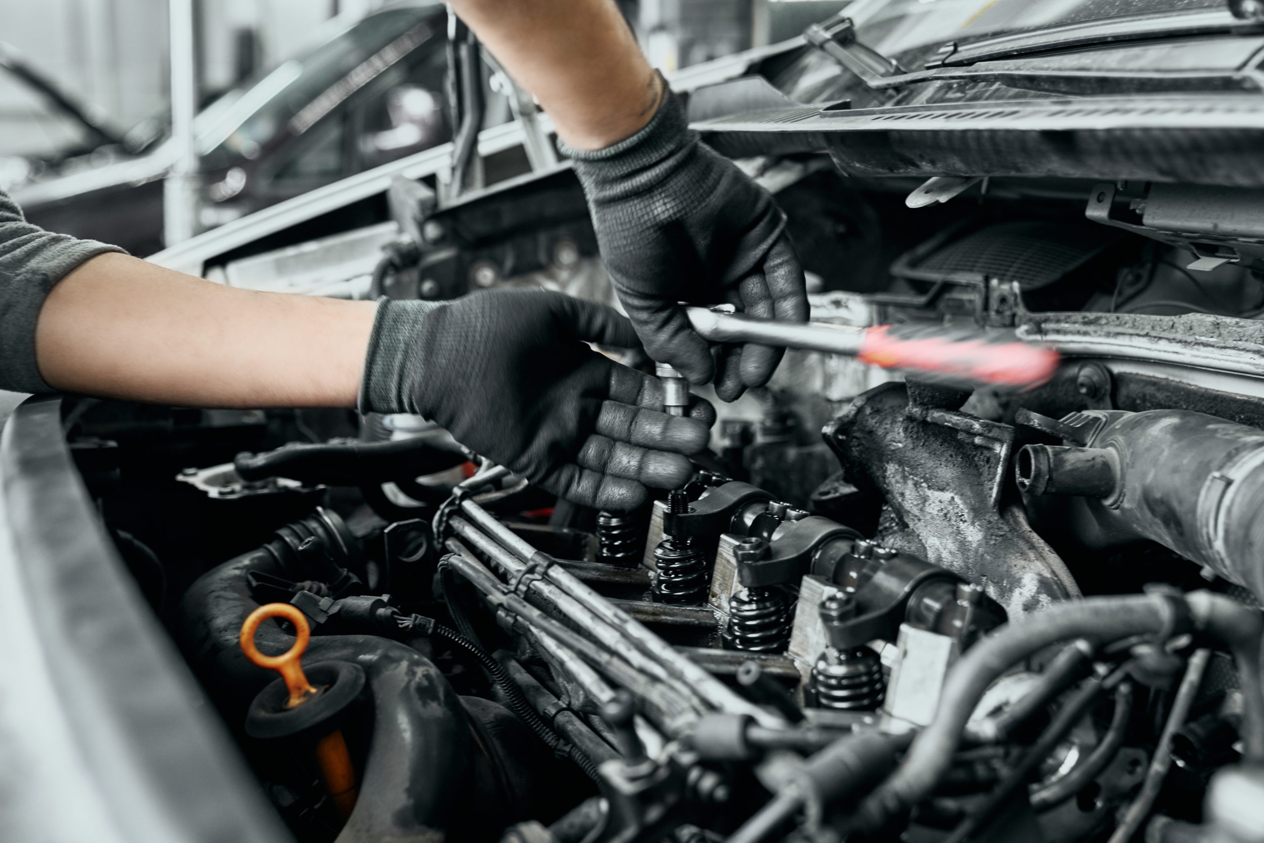 Qualified man in black dirty gloves unscrews old spark plugs